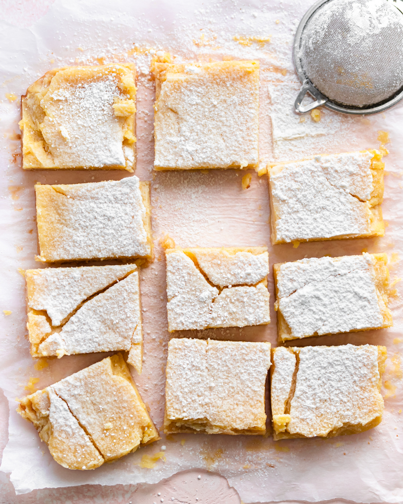 Lemon bars laid out on a pan with powdered sugar