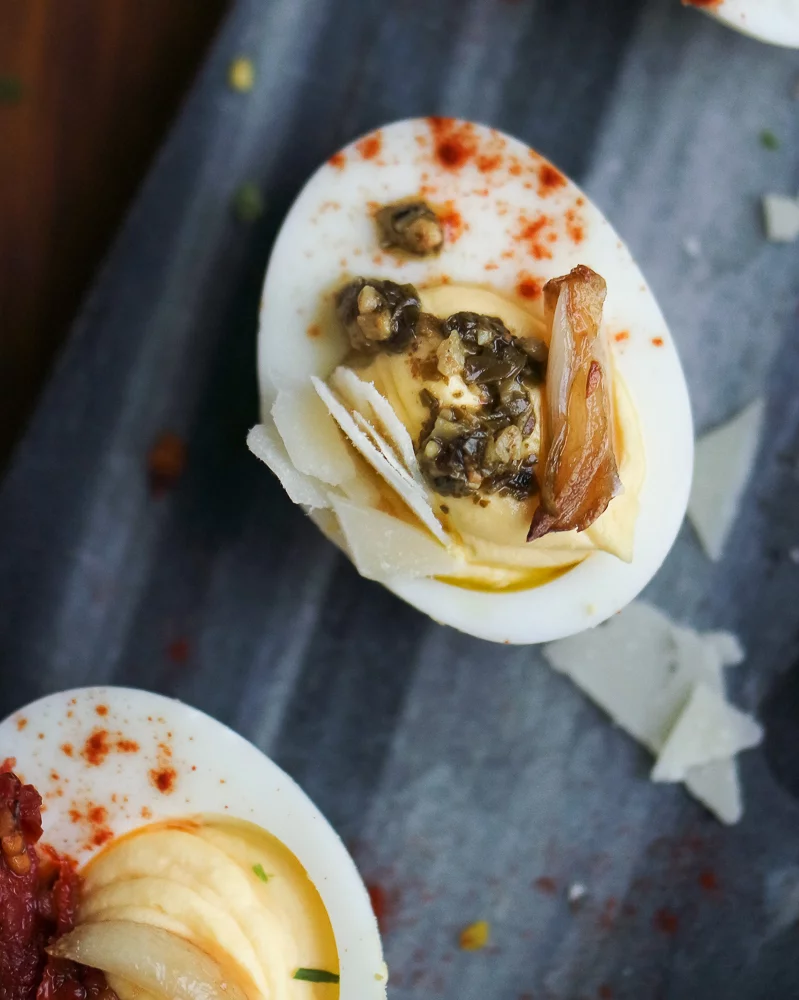 Deviled egg topped with pesto and roasted garlic