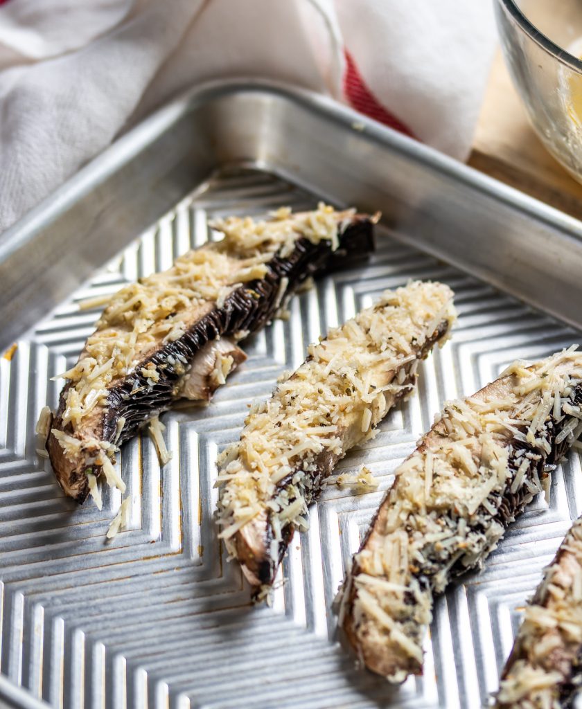 baked portobello mushroom strips with breading on a baking sheet.