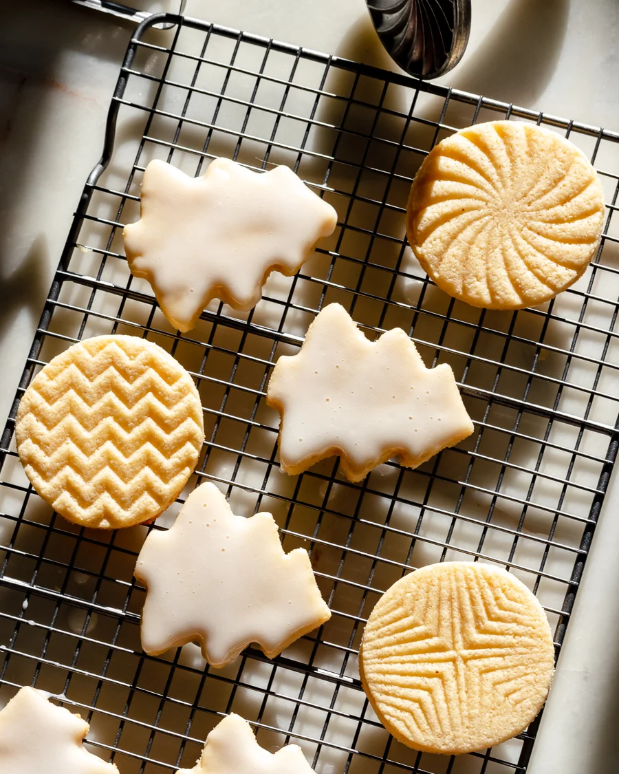 tree shaped sugar cookies with white icing on a wire cooling rack
