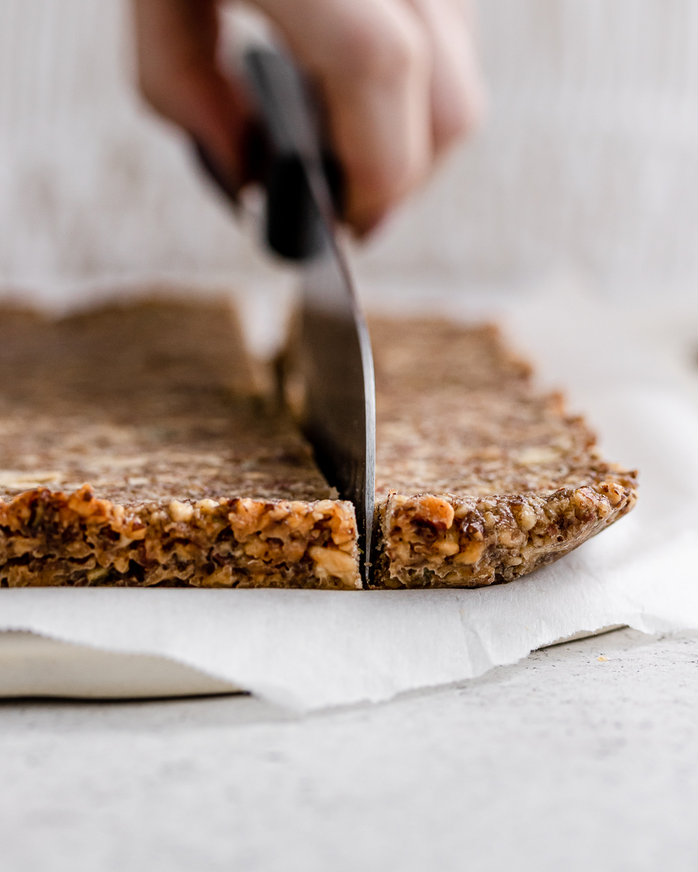 A knife slicing through the granola bar